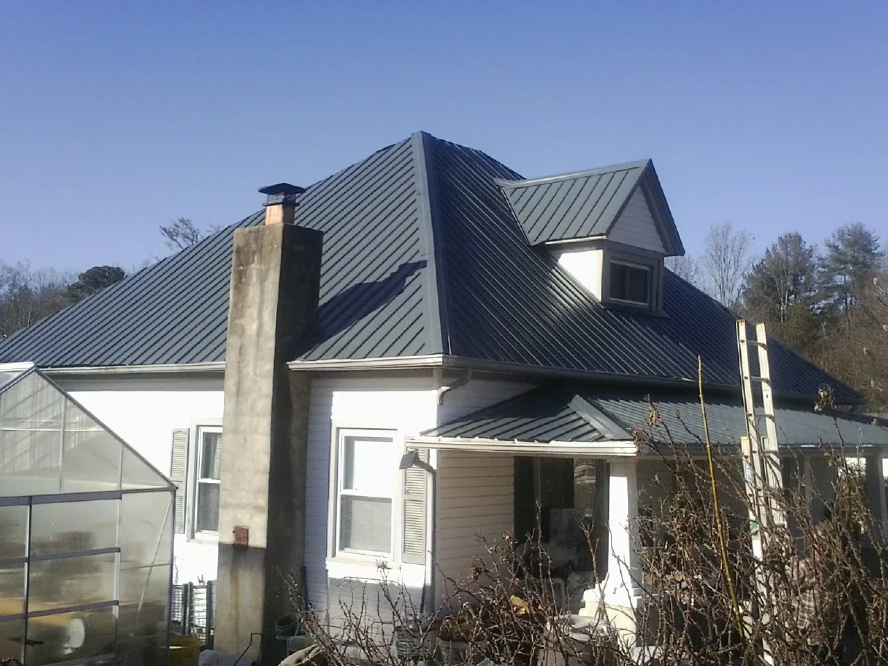 Dark blue standing seam metal roof on a white farmhouse with dormer — Slate & Tile Roof Repair by Roofing Brothers in Little River Academy