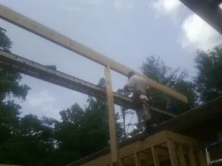 Carpenter setting a ridge beam over a new addition frame — Ice Dam Removal by Roofing Brothers in Little River Academy