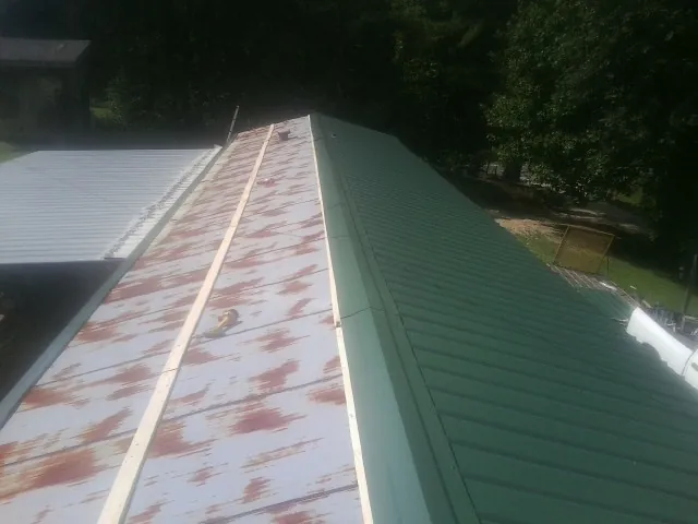 Old rusted panels beside newly installed green metal roofing — Wind Damage Roof Repair by Roofing Brothers in Little River Academy