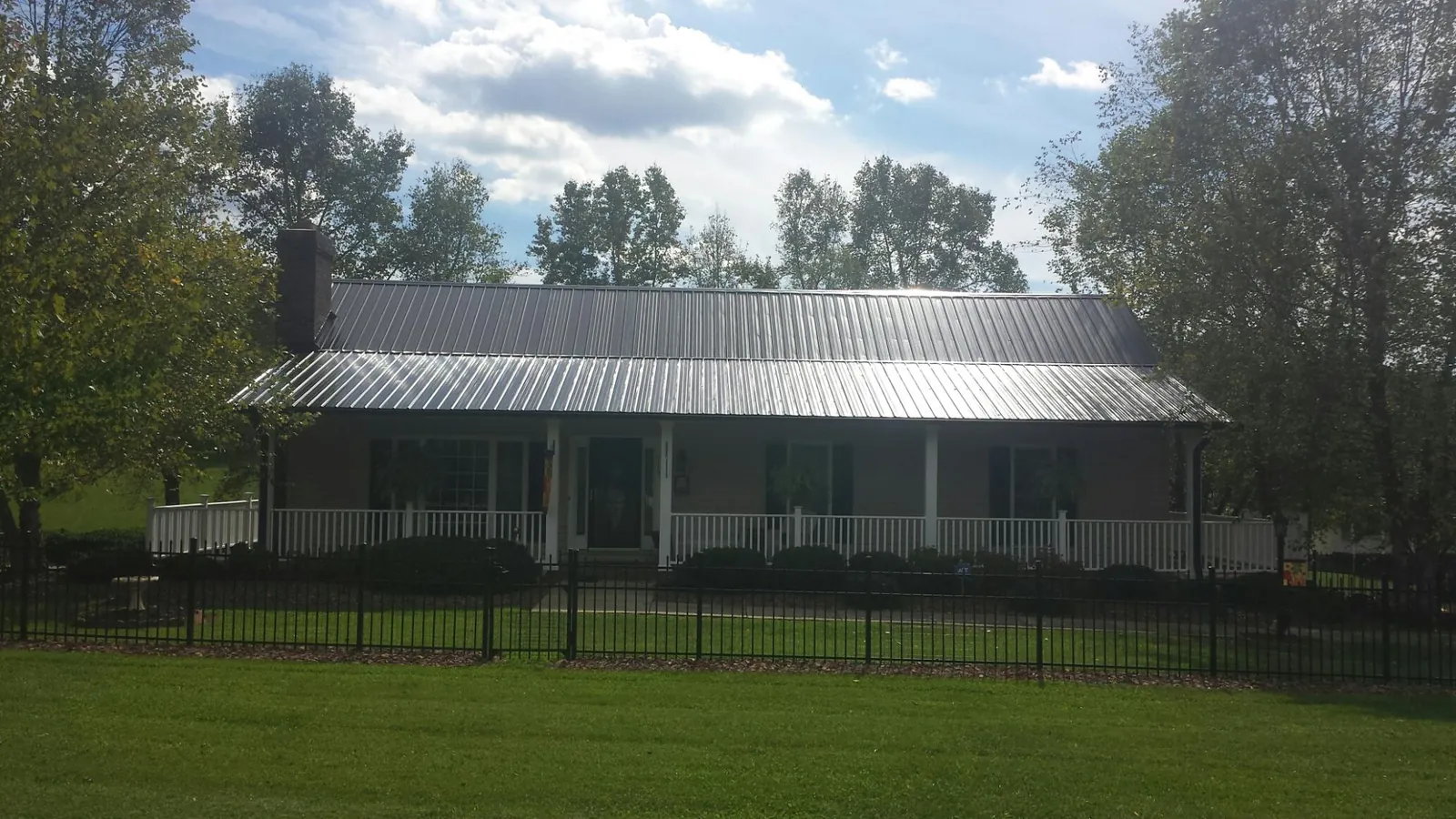 Gray metal roof on a brick ranch with a full width front porch — Gutter Guard Installation work by our crew in Little River Academy