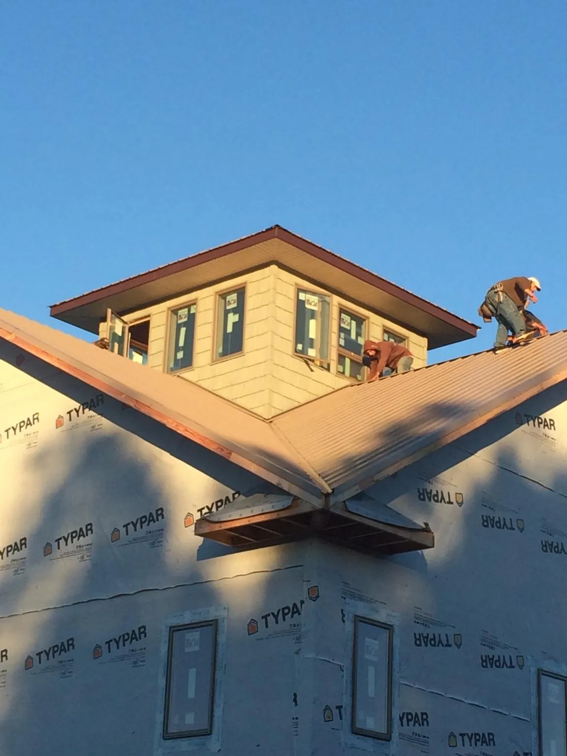 Roofers working around a rooftop cupola on a new metal roof at sunset — Roof Waterproofing in Little River Academy by Roofing Brothers